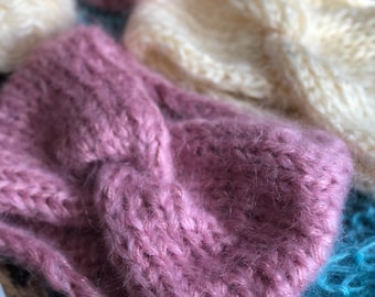 Puede incluir: Primer plano de varias diademas de punto en varios colores. Las diademas son en tonos rosa, crema y turquesa. La textura del tejido de punto es visible, con un aspecto suave y difuso. Las diademas están dispuestas de forma informal y superpuesta.