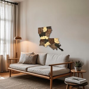 May include: A wooden map of Louisiana, mounted on a wall. The map is made of various shades of brown wood, with each parish outlined and labeled. The map is a decorative piece, likely for home decor or a gift.