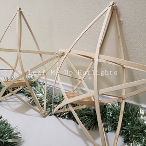 May include: Two unfinished wooden star-shaped frames with a green garland around them. The text "Leaf Me Up Hutlights" is visible in the image.