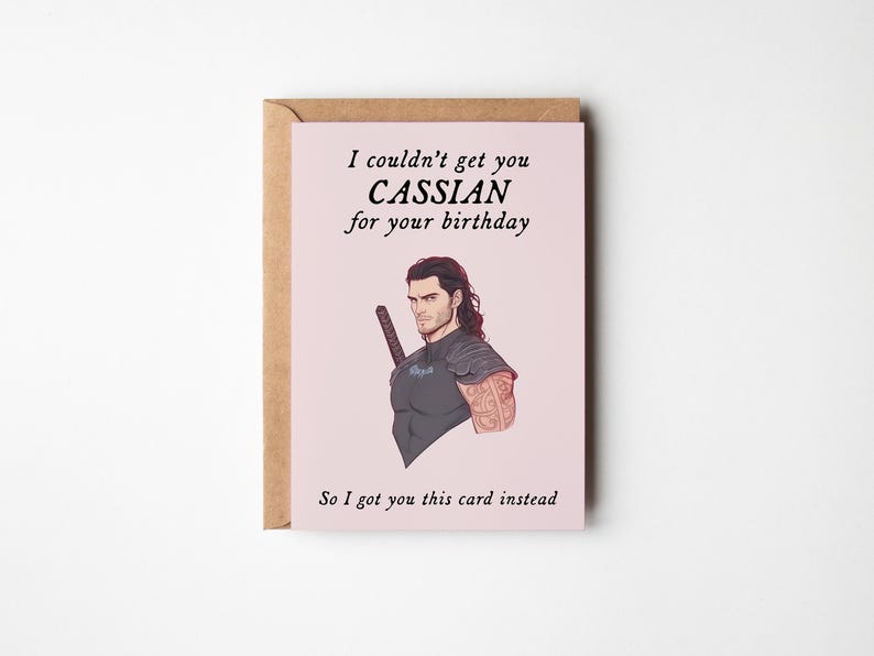 May include: A pink birthday card featuring a cartoon illustration of a man with brown hair and a sword. The card reads "I couldn't get you Cassian for your birthday. So I got you this card instead."