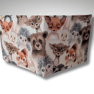 May include: A white fabric wallet with a repeating pattern of various woodland animals, including squirrels, rabbits, foxes, and bears. The animals are depicted in a cartoon style with brown, gray, and orange colors.
