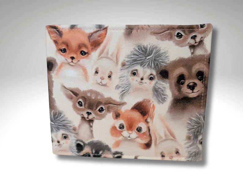 May include: A fabric with a repeating pattern of various woodland animals, including a fox, a deer, a squirrel, a hedgehog, and a rabbit. The animals are depicted in a cartoon style with soft colors and a whimsical feel.