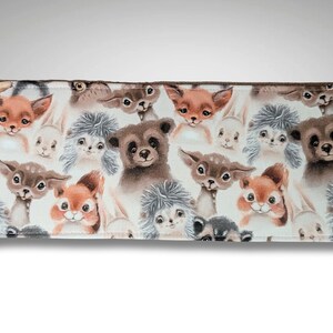 May include: A brown fabric wallet with a white background and a repeating pattern of various woodland animals, including squirrels, foxes, deer, and bears.