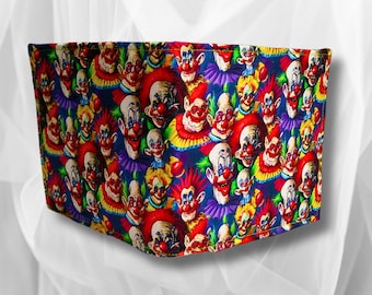 May include: A wallet with a colorful pattern of clown faces. The faces are red, yellow, blue, green, and purple. The background is a dark blue.