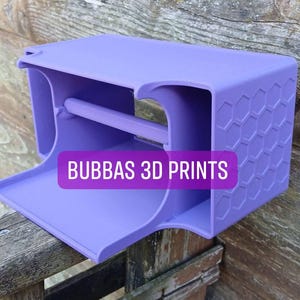 Puede incluir: Un objeto impreso en 3D de color lavanda con forma rectangular, que presenta un estante y un patrón hexagonal en un lado. El texto "BUBBAS 3D PRINTS" se muestra en la parte delantera.