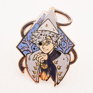 May include: A gold-toned enamel pin featuring a character with white hair, a white hat, and a blue eye patch. The character is wearing a white coat with gold buttons and a purple undershirt. The background is a blue and white diamond-shaped design with a glittery effect.