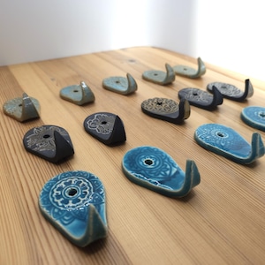 Könnte beinhalten: Eine Sammlung von Keramikhaken mit verschiedenen blauen und schwarzen Mandala-Designs. Die Haken sind tropfenförmig und haben oben ein kleines Loch.