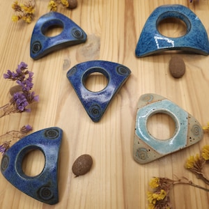 Könnte beinhalten: Fünf keramische, dreieckige Ringhalter mit einem Loch in der Mitte. Die Halter sind in Blau- und Weißtönen mit einem Wirbelmuster glasiert.