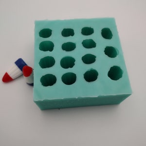 May include: A light blue silicone mould with 18 round cavities. The mould is designed for making small, round objects.