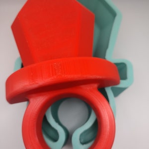 May include: A red ring mould with a large, faceted top. The mould is made of silicone and is designed to create a ring with a large, prominent stone.