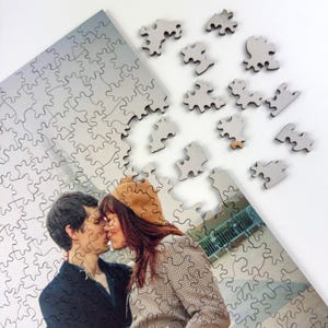 Custom wooden photo puzzle partially assembled with loose jigsaw pieces, personalized puzzle made from a romantic couple photo.