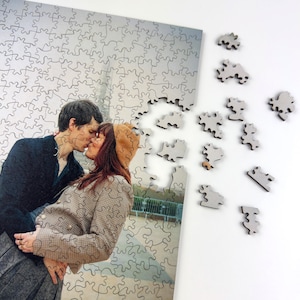 Custom wooden photo puzzle with scattered puzzle pieces, personalized jigsaw puzzle made from a couple photo printed on a premium wooden puzzle.