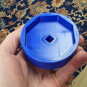 May include: A blue plastic octagonal-shaped tool with a square hole in the center.