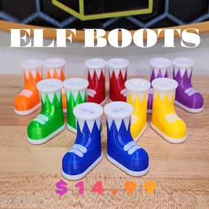May include: A set of ten elf boots in various colors, including red, green, blue, yellow, and purple. The boots are made of plastic and have a white trim. The boots are arranged in a row on a wooden surface. The text "ELF BOOTS" is displayed above the boots. The price is shown below the boots as "$14.99".