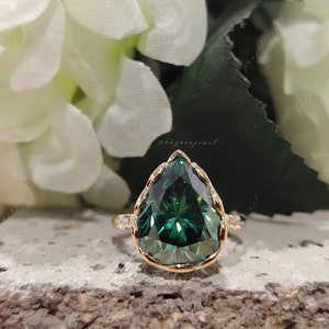 May include: A pear-shaped green gemstone ring with a gold band and small diamonds set around the stone.