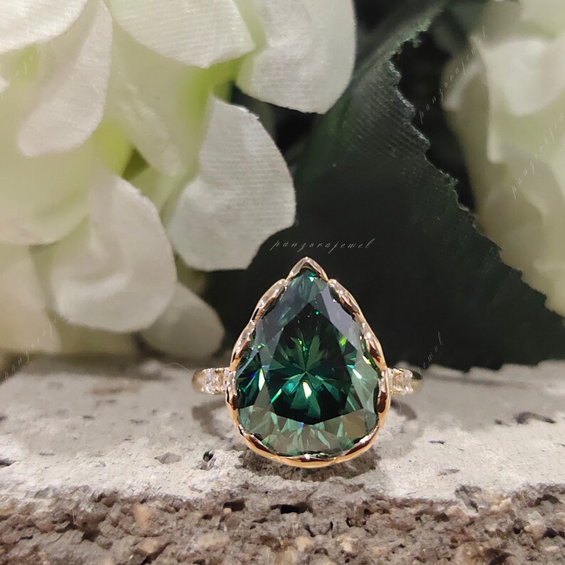 May include: A pear-shaped green gemstone ring with a gold band and small diamonds set around the stone.