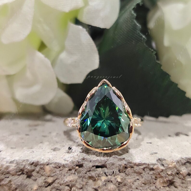 5ct dark green moissanite ring
pear cut green moissanite ring gold
bezel set big stone engagement ring
18k gold green statement ring
unique green diamond look ring
bold pear shape engagement ring
moissanite ring close up sparkle
fine jewelry green bridal ring
anniversary gift ring for her
luxury green gemstone ring
modern bezel set engagement ring
eye catching statement ring design