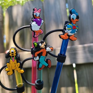 Puede incluir: Cuatro pajitas de colores con diferentes personajes de Disney. Los personajes son Mickey Mouse, Donald Duck, Goofy y Minnie Mouse. Las pajitas son transparentes, azules, rosas y amarillas.