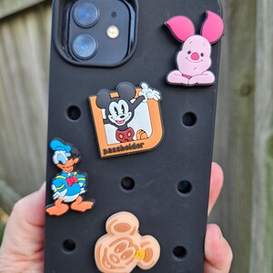 Könnte beinhalten: Schwarze Handyhülle mit Mickey Mouse, Donald Duck und Ferkel Charakterdesign. Die Hülle hat einen Kartenhalter und ein Mickey Mouse Kopfdesign.