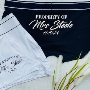 May include: Two pairs of underwear, one white and one black, with the text "PROPERTY OF Mrs. Steele 11.10.21" printed on them.