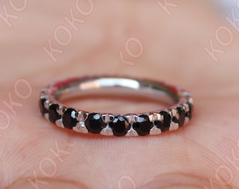 May include: A silver band ring with a row of black gemstones.