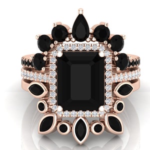Puede incluir: Un juego de anillos de oro rosa con una gran gema negra rectangular rodeada por un halo de pequeños diamantes blancos. Gemas negras adicionales y elementos decorativos adornan el diseño del anillo. El conjunto incluye múltiples anillos.
