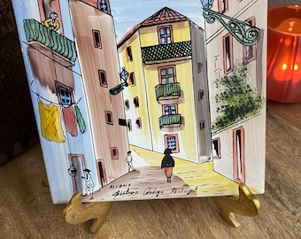 Azulejo cerâmico vintage pintado à mão, representando uma cena de rua no bairro de Alfama, em Lisboa, Portugal.