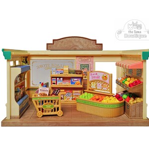 May include: A miniature toy grocery store with shelves stocked with food items, a shopping cart, and a display of fresh fruits. The store has a sign that says "Village Store" and "Fresh Fruit".