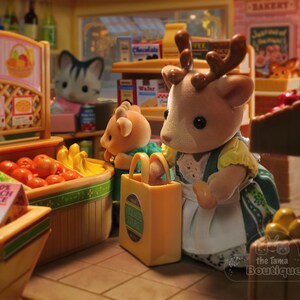 May include: A miniature grocery store scene with animal figurines. A deer figure holds a shopping bag. Baskets display fresh fruit, including tomatoes and bananas. A sign reads "Fresh Fruit". Other figures and shelves with products are visible.