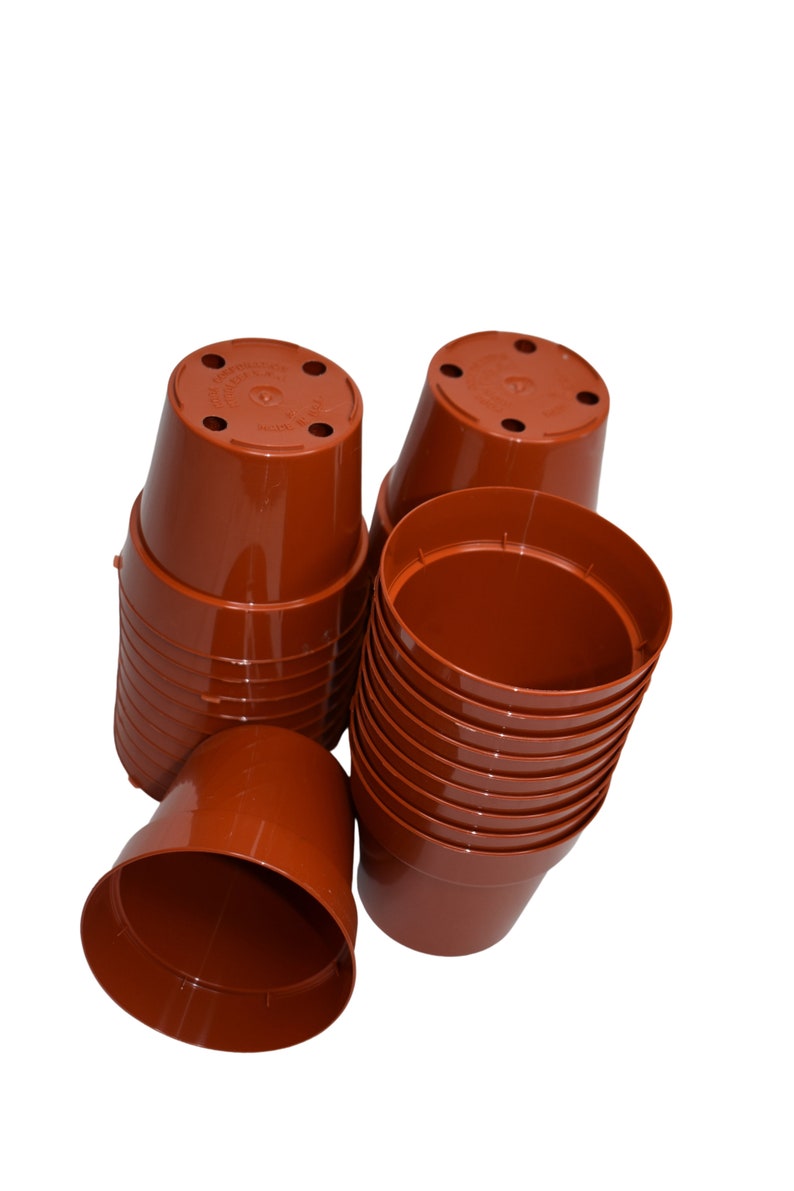 May include: A stack of brown plastic plant pots, some are stacked and some are loose. The pots are all the same size and have drainage holes in the bottom.