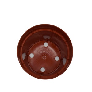 May include: A terracotta colored plastic plant pot with four drainage holes in the bottom.