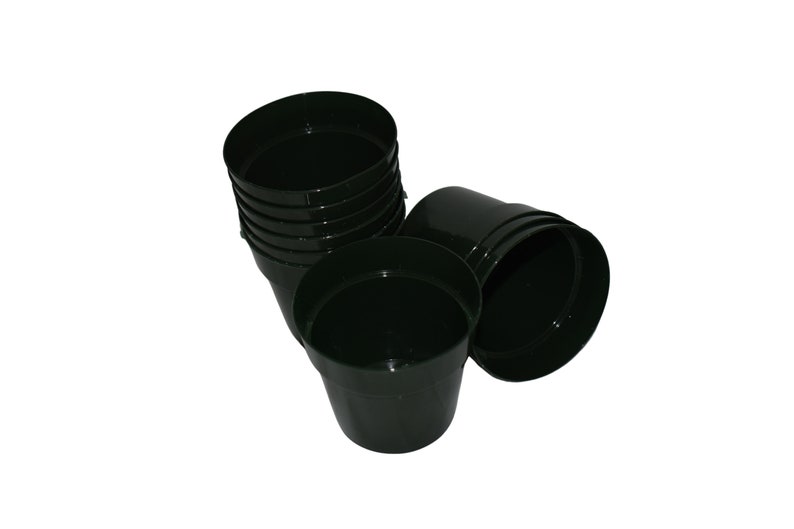 Puede incluir: Un conjunto de macetas de pl&aacute;stico negro. Las macetas son redondas y tienen una superficie lisa.