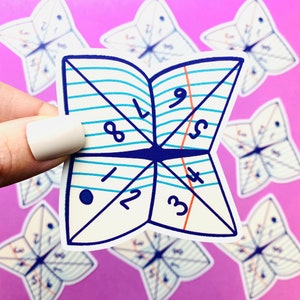 Peut inclure: Un autocollant blanc en forme de papillon, avec des lignes bleues et les chiffres de 1 &agrave; 9. L'autocollant est tenu sur un fond violet avec d'autres autocollants similaires.