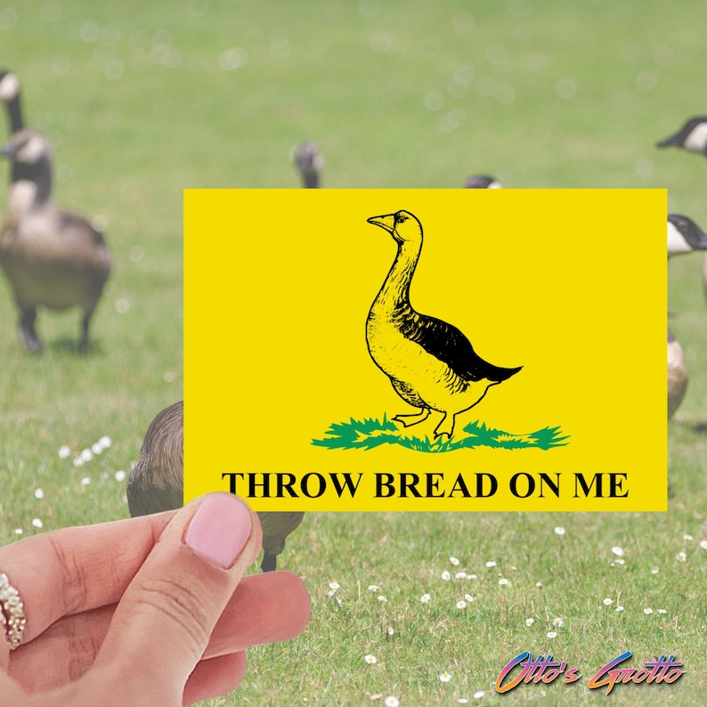 May include: A yellow sign with a black and white illustration of a goose. The sign reads "Throw Bread On Me".