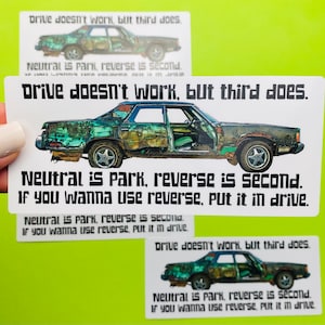 May include: White sticker with a graphic of a rusty car and the text "Drive doesn't work, but third does." and "Neutral is park, reverse is second. If you wanna use reverse, put it in drive."