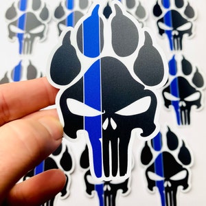 May include: Black and gray paw print skull stickers with a blue stripe. The stickers feature a skull design with a paw print outline, and a vertical blue stripe down the center. Several stickers are visible.