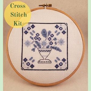 May include: Cross stitch kit featuring a blue and white floral design in a vase. The design is framed in a wooden embroidery hoop.