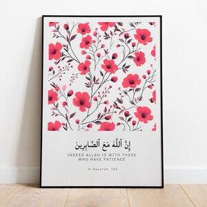 May include: A framed print with a white background and a floral pattern of pink flowers and dark gray stems. The print includes an Arabic quote and its English translation: "Indeed Allah is with those who have patience." The quote is attributed to Al-Baqarah 153.