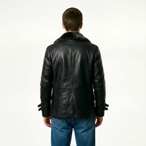 May include: Black leather jacket with a faux fur collar, featuring a button-down front and two side pockets. The jacket has a classic design with a tailored fit, perfect for cold weather. The model is wearing blue jeans.