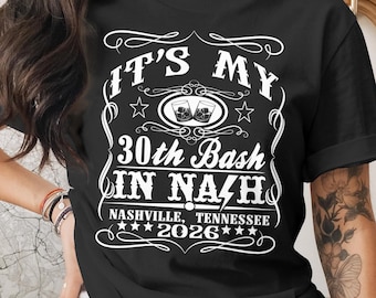 May include: Black t-shirt with white text that reads "IT'S MY 30th Bash IN NASHVILLE, TENNESSEE 2026". The design includes two cocktail glasses and decorative flourishes. A casual tee for a birthday celebration.