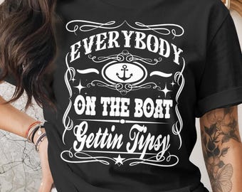 May include: Black t-shirt with white text that reads "EVERYBODY ON THE BOAT Gettin Tipsy". The design includes an anchor, stars, and decorative flourishes. The shirt is a casual wear item.