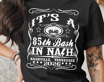 May include: Black t-shirt with white text that reads "IT'S A 85th Bash IN NAZH NASHVILLE, TENNESSEE 2026". The design includes two glasses of whiskey, stars, and decorative flourishes.