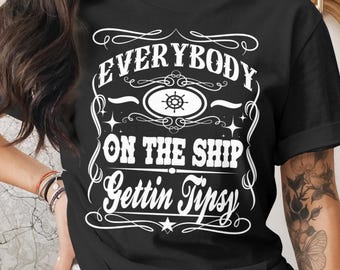 May include: Black t-shirt with white text that reads "EVERYBODY ON THE SHIP Gettin Tipsy." The design includes a ship's wheel and decorative flourishes. The shirt is a crew neck style.