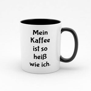 Op de afbeelding: Witte keramische mok met een zwarte rand en handvat. De mok heeft zwarte tekst met de tekst "Mein Kaffee ist so heiß wie ich."