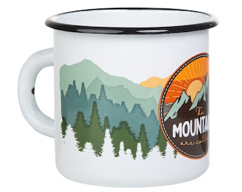 Może przedstawiać: Biały kubek emaliowany z czarną obwódką. Kubek przedstawia grafikę pasma górskiego z zachodem słońca i tekstem "The Mountains are calling".