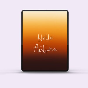 May include: A black tablet shows an autumnal gradient background, shifting from orange to brown. The words "Hello Autumn" are written in a delicate, white script, creating a seasonal greeting.