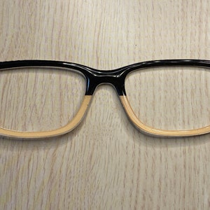 May include: Black and tan eyeglasses with a gold logo on each side of the frame.