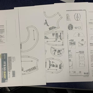 May include: A sewing pattern for a bear costume. The pattern includes instructions for making a bear head, body, and legs. The pattern is printed on white paper and includes the text "A2115 IT'S SO EASY IT'S Simplicity &pound;7.97".