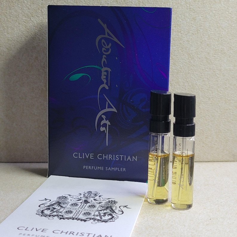 May include: A Clive Christian perfume sampler box with the text "Addict Art" and "Clive Christian Perfume Sampler". The box contains two small glass vials of perfume.