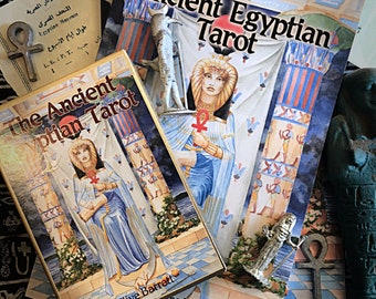 May include: The Ancient Egyptian Tarot deck features a colourful illustration of a woman in a blue robe holding a staff. The card is titled "The Ancient Egyptian Tarot" and the author is Clive Barrett.